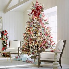 a decorated christmas tree in a living room with white furniture and red bows on it