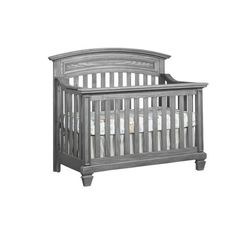 a gray crib with white sheets on it