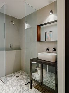 a bathroom with a glass shower door, sink and mirror on the wall next to it