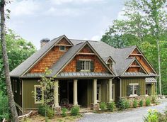 a large house in the woods with lots of trees and bushes around it's entrance