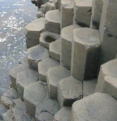 the large rocks are lined up along the water's edge, and they have holes in them