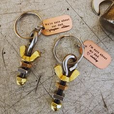 two metal key chains sitting next to each other on top of a wooden table with words written on them