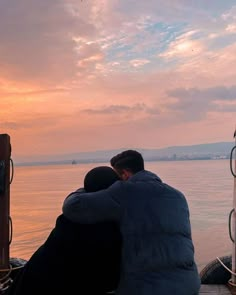 two people sitting on a boat looking out at the water