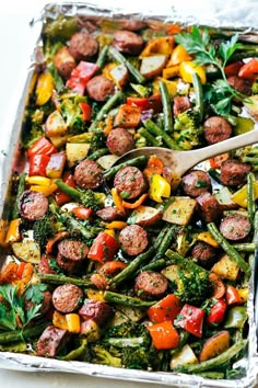 sausage and veggies in a pan with a wooden spoon on the side, ready to be eaten