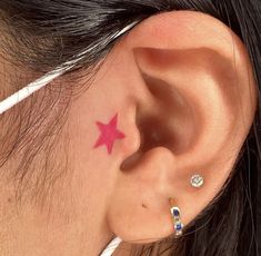 a woman with a pink star tattoo behind her ear