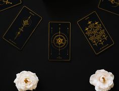 some white flowers and cards on a black table with gold foiling around the edges