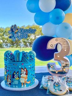 a blue birthday cake and balloons on a table with the number 3 in front of it