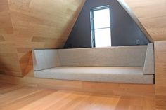 an empty room with wooden floors and a couch in the corner, looking out into the window