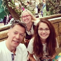 three people sitting at a table smiling for the camera