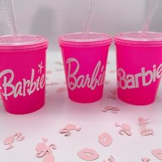 three pink plastic cups with straws in each one that say barbie, barbie and barbie