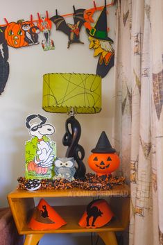 halloween decorations are displayed on a table in front of a wall with bats and pumpkins