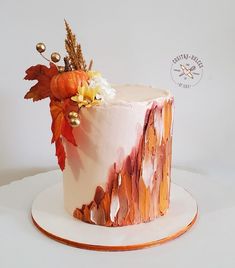 a cake decorated with leaves and flowers on top of a white plate, sitting on a table