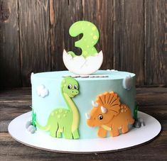 a dinosaur themed birthday cake with the number three on it's top and two small dinosaurs