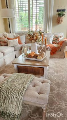 a living room filled with furniture and a coffee table in front of a window on top of a rug