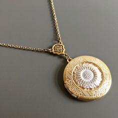 "White Sunflower Locket Necklace - Antiqued Gold and White Plated Sunflower attached to Antiqued Gold and White plated Locket with a pretty floral design.  The locket dangles from an Antiqued Gold plated Flower Connector. The Locket is approximately 30 mm (1.25\") in diameter. Antiqued Gold plated Chain For other sunflower designs:  https://www.etsy.com/shop/mcstoneworks/search?search_query=sunflower&order=date_desc&view_type=gallery&ref=shop_search For other locket designs: http://www.etsy.com/ Adjustable Vintage Flower Shaped Jewelry, Wedding Jewelry With Sunflower Design, Vintage Gold Jewelry With Flower Charm, Adjustable Flower Charm Necklace For Wedding, Antique Engraved Flower Jewelry, Antique Flower Engraved Jewelry, Adjustable Wedding Flower Necklace With Charm, Vintage Jewelry With Flower Charm For Anniversary, Vintage Brass Jewelry With Flower Charm