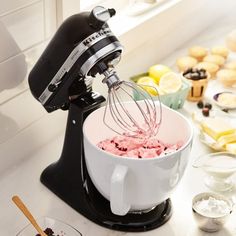 a mixer filled with ice cream sitting on top of a counter next to other bowls