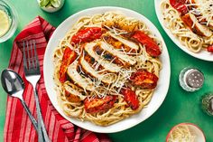 two plates of spaghetti with meat and sauce on the side, next to silverware