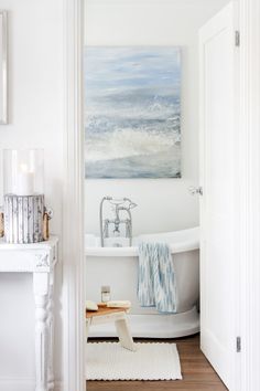 a bathroom with a white bath tub sitting next to a painting on the wall above it