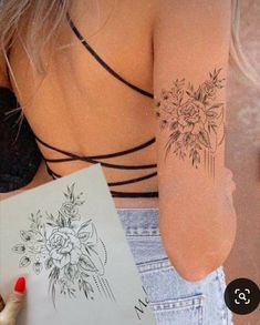 the back of a woman's shoulder with flowers on it and a tattoo design