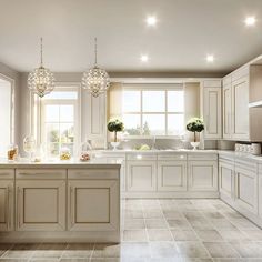 a large white kitchen with lots of counter space and lights hanging from the ceiling over the island