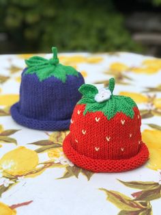 two knitted hats sitting on top of a table