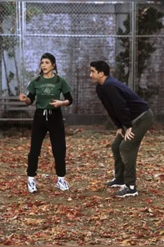 two people are playing frisbee in the leaves