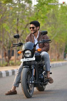 a man riding on the back of a motorcycle down a street