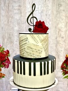 a three tiered cake decorated with music notes and a red rose