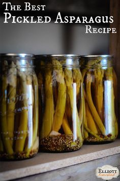 three jars filled with pickled asparagus sitting on top of a shelf