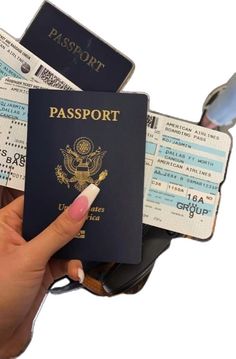 a woman's hand holding a passport and boarding tickets