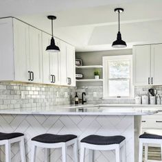 three stools are sitting at the bar in this white kitchen with herringbone backsplash