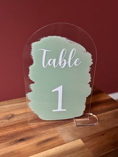 a clear acrylic table number holder on a wooden table with a red wall in the background