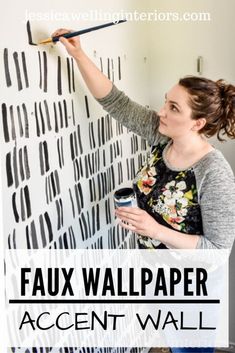 a woman painting a wall with black and white stripes on it, the text reads faux wallpaper accent wall