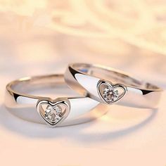 two white gold wedding rings with diamonds in the shape of hearts on a light background