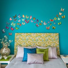 a bedroom with blue walls and colorful butterflies on the wall above the bed, along with two nightstands