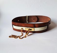 Vintage authentic Moschino Redwall women belt, patent leather in brown and ivory, gold tone hardware. Signed: Redwall Made in Italy All Genuine Leather 401017 MOSCHINO.  Minor loss of gold tone in one place on the buckle and  tiny spots on the skin/see last photo/. Very good vintage condition. Measurements: will fit waists: 71cm/ 28 in  to 77cm/30.2 in - maximum wide - 6 cm/2.4 in Brown Leather Belt With Gold-tone Logo Plaque, Designer Brown Belt With Gold Buckle, Designer Brown Belts With Gold-tone Hardware, Luxury Brown Belts With Gold-tone Hardware, Luxury Belts With Brass Hardware, Designer Formal Belts With Brass Hardware, Designer Leather Belt With Brass Hardware, Luxury Brown Belt With Brass Hardware, Luxury Brown Belts With Brass Hardware