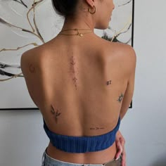 a woman with tattoos on her back standing in front of a painting