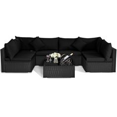 a black couch and coffee table on a white background with flowers in vases next to it