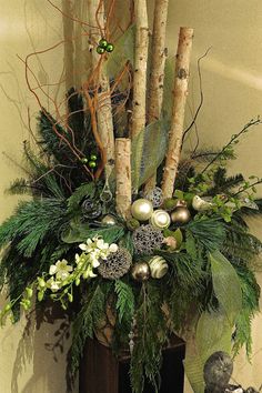 a vase filled with greenery and ornaments on top of a wooden table next to a wall