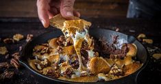 a person is dipping some food into a skillet