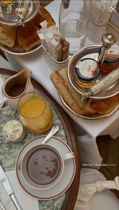 a table topped with plates and bowls filled with food covered in sauces next to bread