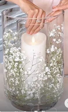 a woman is holding a candle in a vase with flowers