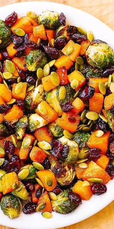 a white plate topped with brussel sprouts and carrots on top of a wooden table