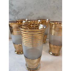 four gold and grey glass cups sitting on top of a table next to each other