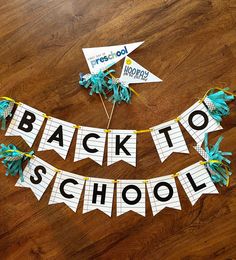 the back to school banner is made out of construction paper and blue streamers on a wooden floor