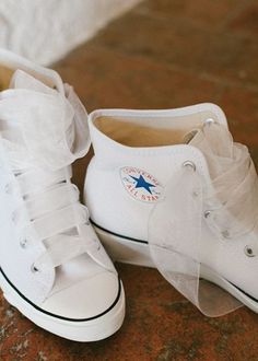 two pairs of white shoes with bows on the bottom and one shoe has a star sticker on it