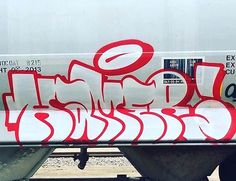 graffiti on the side of a train car that has been vandalized with red and white spray paint