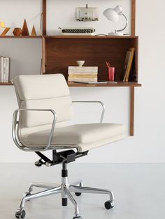 a white office chair sitting in front of a book shelf