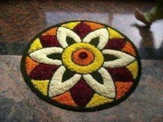 a circular rug with an orange, yellow and red flower on it