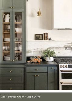 a kitchen with green cabinets and an oven in the center, surrounded by white marble countertops